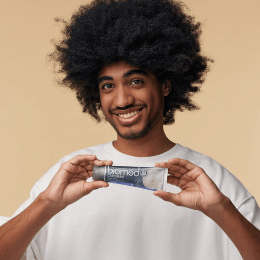 Man holding Biomed toothpaste, smiling and showcasing the best toothpaste for your smile.